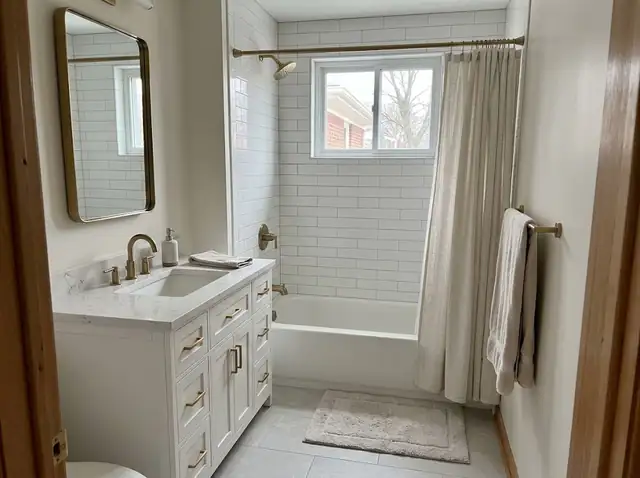 Updated bathroom with white shaker vanity, brass pulls and white tile (illustration)